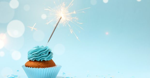 Cupcake wth one sparkler on a blue background