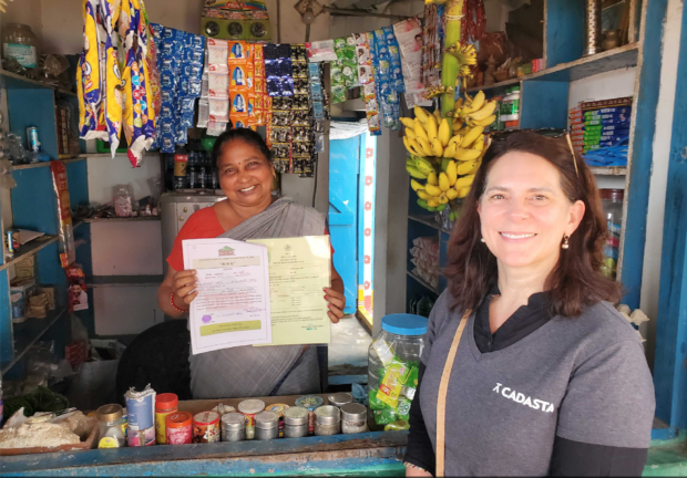 Amy Coughenour Betancourt with Ampol Satyavathi, showing her land ownership documents in a small shop
